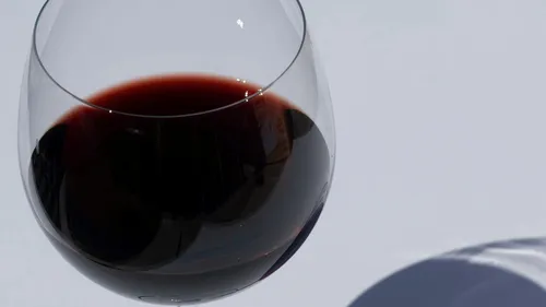 Ein Weinglas mit rotem Wein steht auf einer Tischoberfläche.